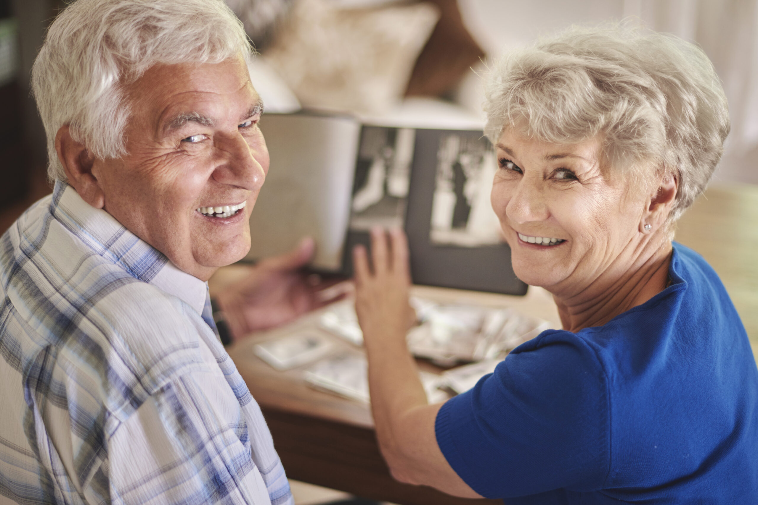 Older couple looking at camera while opening photo book